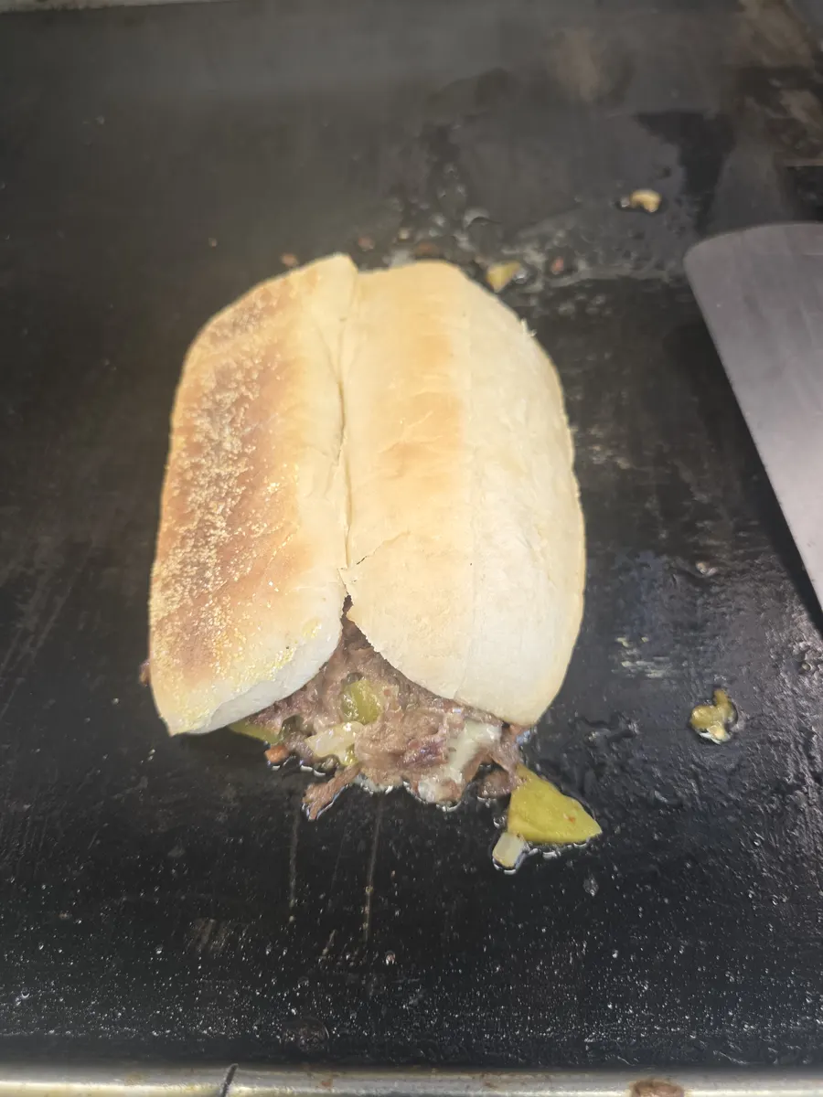 The loaded hoagie roll closed up and finishing on the griddle