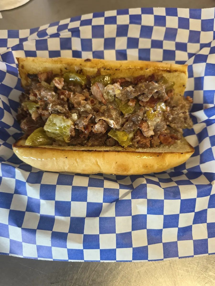 The finished Duke, open-faced in a blue checkered basket, piled with steak, hotlink, green chile and melted cheese